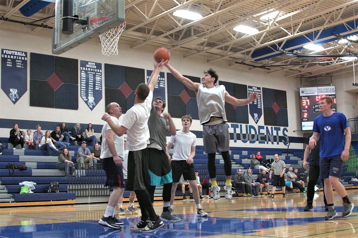 Player of Team Rice and Bennets goes for a lay in over the head of Caleb Blackmore of Team Blackmore in the first round of the Men's Alumni Basketball Tournament.