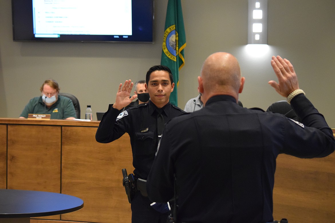 Jerry Martinez is sworn in by Quincy Police Department Chief Kieth Siebert (foreground) as a new police officer at a city council meeting in mid-December.