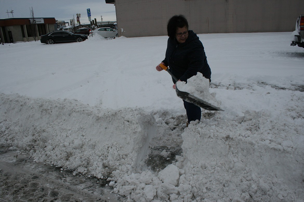 Ronda Vance shovels a section of the snow berm at the parking lot of her business on Moses Lake’s Fourth Avenue Thursday morning.