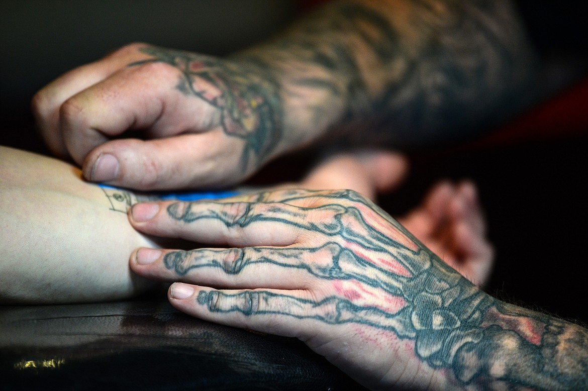 Ryan Swindler places an adhesive healing bandage on Bridger Beach's finished tattoo at Swindler Ink in Kalispell on Wednesday, Jan. 5. (Casey Kreider/Daily Inter Lake)