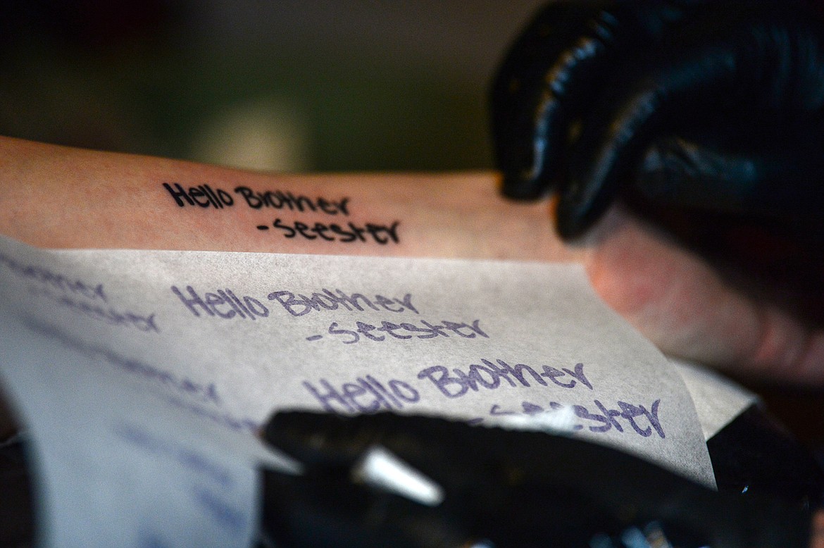 Ryan Swindler compares a sketch to the finished tattoo on Bridger Beach's forearm at Swindler Ink in Kalispell on Wednesday, Jan. 5. (Casey Kreider/Daily Inter Lake)