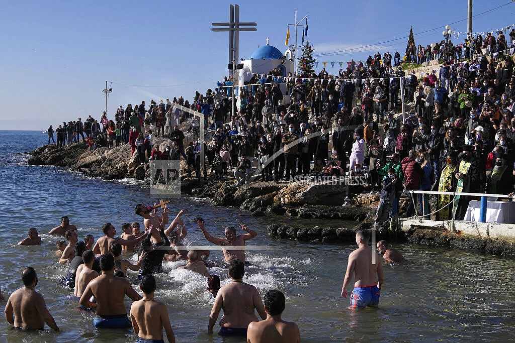 Pilgrims jump to catch the cross during a water blessing ceremony marking the Epiphany celebrations at Piraeus port, near Athens, Thursday, Jan. 6, 2022. Celebrations to mark the Christian holiday of Epiphany were canceled or scaled back in many parts of Greece Thursday as the country struggles with a huge surge in COVID-19 infections driven by the omicron variant. (AP Photo/Thanassis Stavrakis)