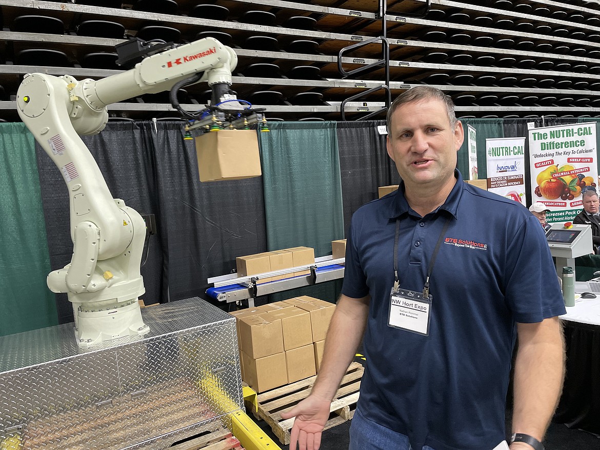 BTB Solutions principle engineer Nathan Rommel stands in front of the portable packing arm he designed and his company sells as it moves boxes.