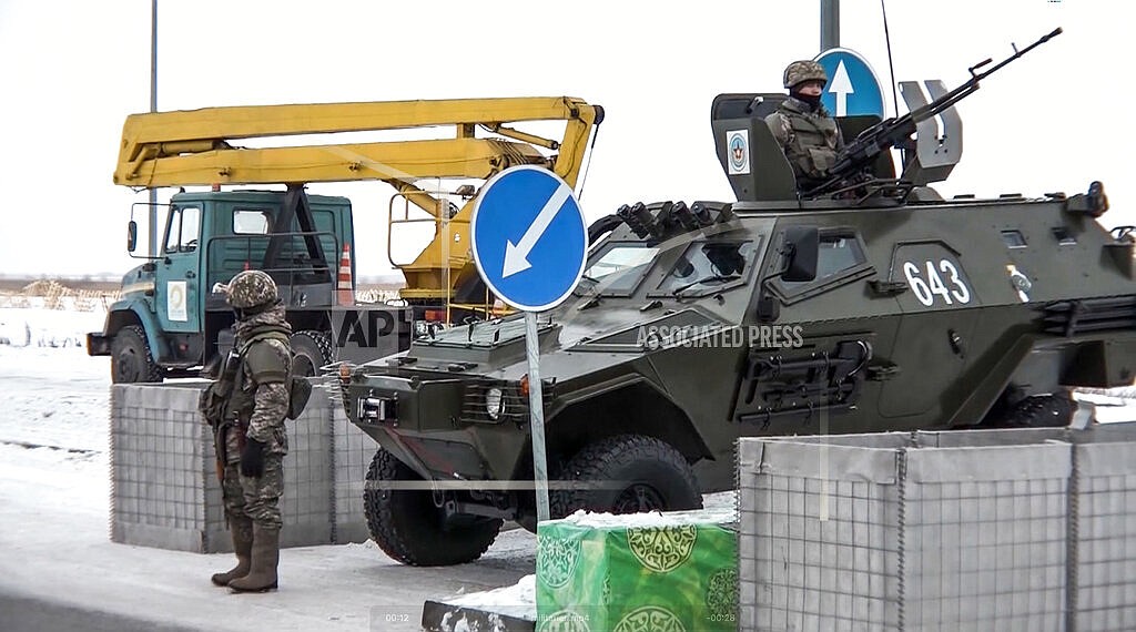 In this image taken from footage provided by the RU-RTR Russian television, A Kazakhstan's soldier stands next to a military vehicle at a check point in Kazakhstan, Friday, Jan. 7, 2022. Over 70 cargo planes are being deployed in Russia's peacekeeping mission in Kazakhstan according to the Defense Ministry chief spokesman's briefing on Friday, after the worst street protests since the country gained independence three decades ago. The demonstrations began over a near-doubling of prices for a type of vehicle fuel and quickly spread across the country, reflecting wider discontent over the rule of the same party since independence. (RU-RTR Russian Television via AP)