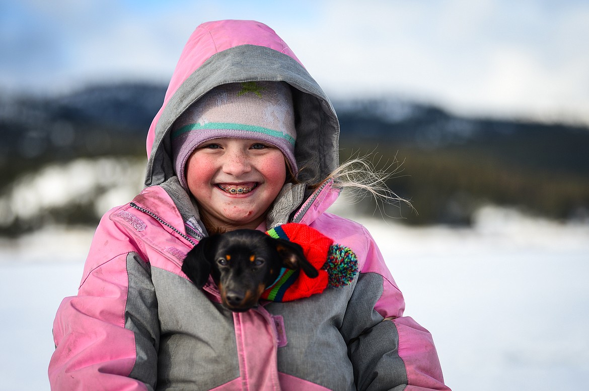 Alina Johnson, 9, of Columbia Falls, keeps her family's mini dachshund named Coco warm inside her coat at the 51st Sunriser Lions Family Ice Fishing Derby at Smith Lake in Kila on Saturday, Jan. 8. (Casey Kreider/Daily Inter Lake)