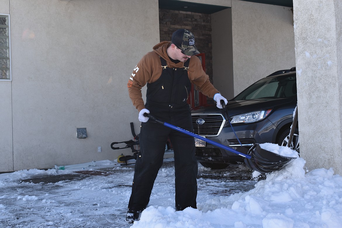 Jeff Gallaher shovels snow left behind by his plow truck.