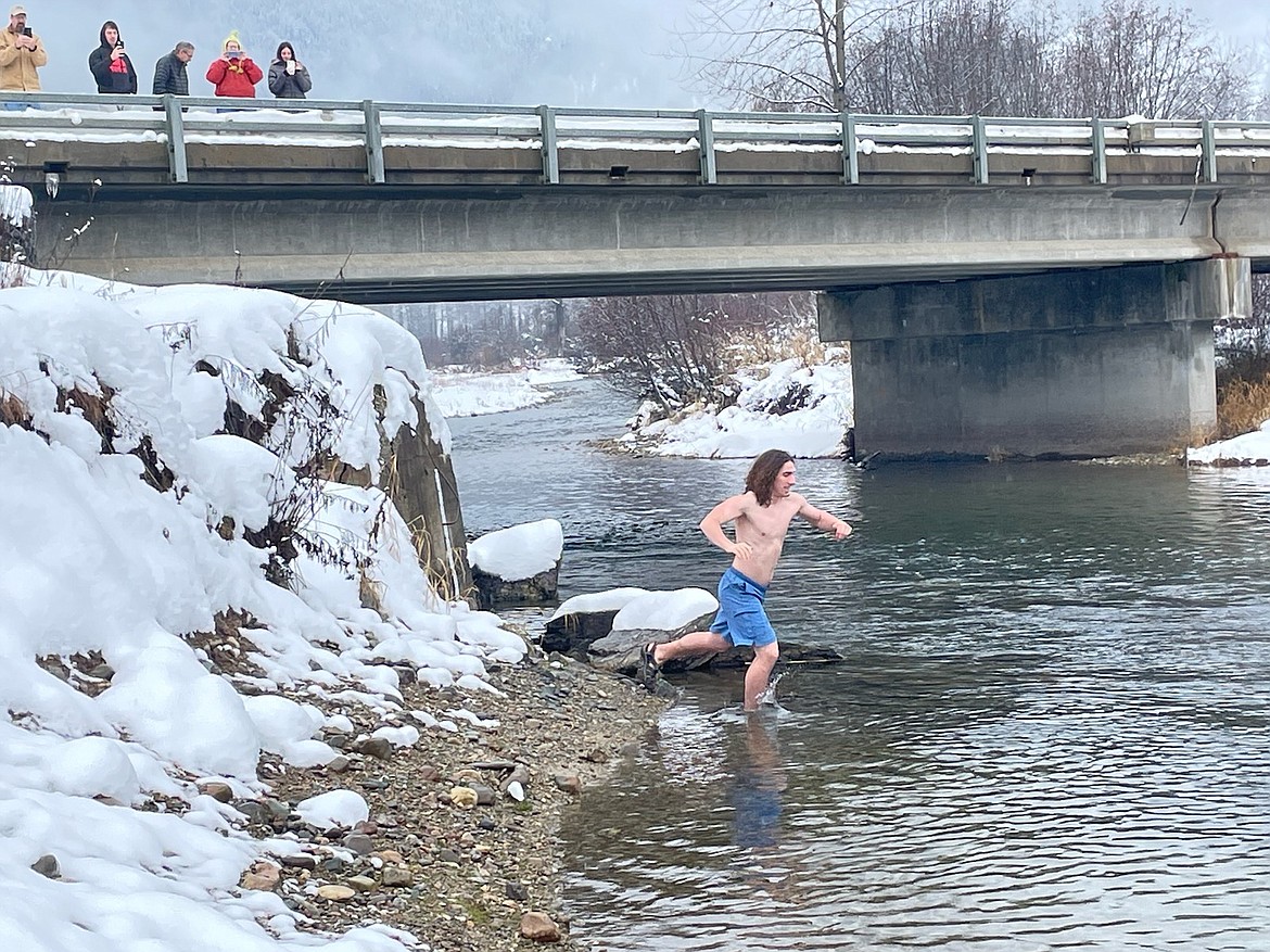 Carter Durkin, of Spokane runs into the St. Regis River last month in December for his monthly swim challenge. He started his ambitious goal of taking a dip at his favorite swimming hole once a month for a year last June. His family looks on and cheers for him from the bridge above. (Photo courtesy Carter Durkin)