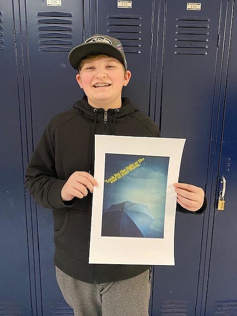 Cash Schmidt, an eighth grader at Lakes Middle School, holds up his work, "Light in the Storm," an art response to the reading of a play adaption of "The Diary of Anne Frank." Schmidt said the light symbolizes hope in the darkness. Courtesy photo