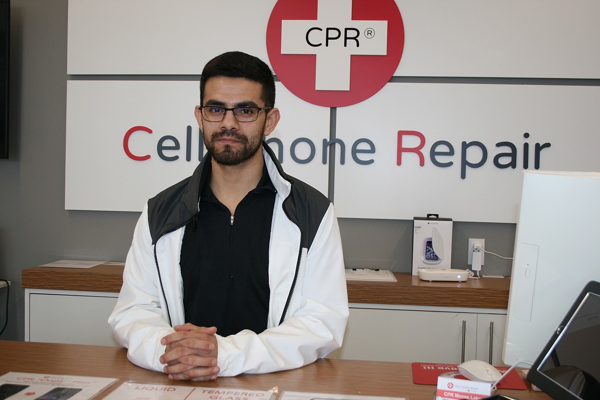 Saul Hinojosa, manager at CPR Cell Phone Repair in Moses Lake, stands behind the counter.
