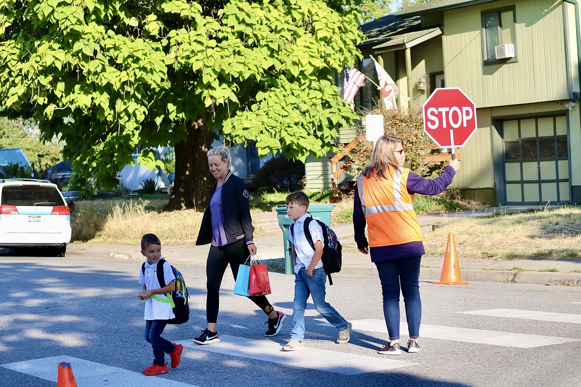 In this Sept. 7 photo, kindergartner Wylee Nyist crosses the road with Arielle Henyel and older brother Vincent to get to the first day of class at Winton Elementary School. The Coeur d'Alene School District announced Thursday the possibility of temporary closures of buildings and programs due to staff shortages from COVID-19 and other illnesses. HANNAH NEFF/Press