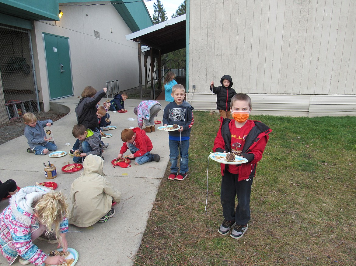 Idaho Hill Elementary kindergartners have fun as they work to make pinecone bird feeders at the school recently.