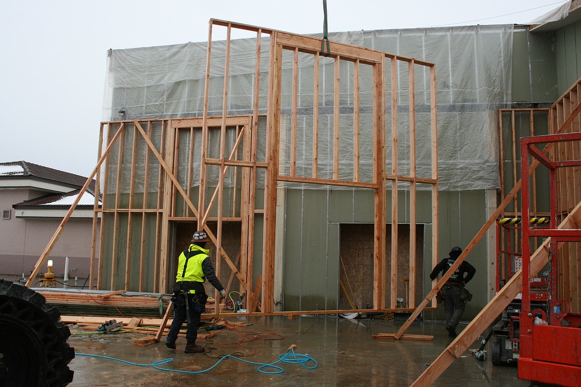 Construction workers walk a framing wall into place during the second phase of construction at Royal High School on Thursday.