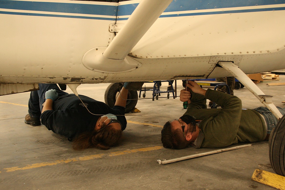 Alexander Ignacio-Gamez (left) and Caleb McGrady (right) remove inspection panels from the underside of an aircraft on Wednesday, during class in the Big Bend Community College aviation maintenance technology program.