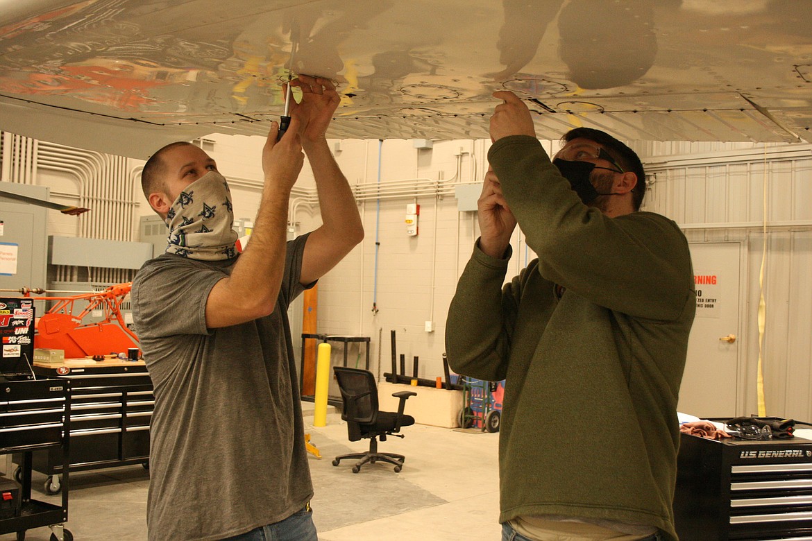 Big Bend Community College aviation maintenance technology students Michael Veenendaal (left) and Caleb McGrady (right) remove inspection panels from an aircraft wing during a Wednesday class.