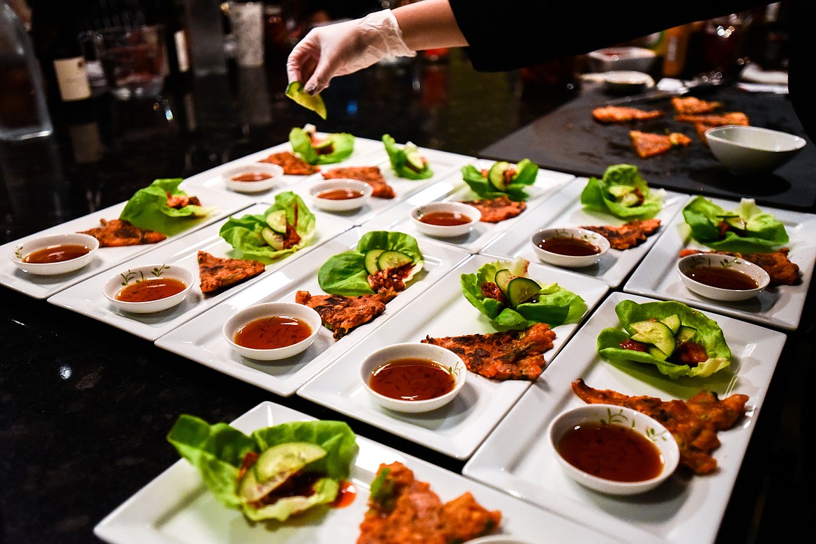 Trovare co-owner Mallory Hickethier places cucumber slices on individual Kimchi Pancake & Braised Pork Belly Lettuce Wraps for attendees of a hands-on cooking class with chef John Evenhuis at Trovare in Whitefish on Tuesday, Jan. 18. (Casey Kreider/Daily Inter Lake)