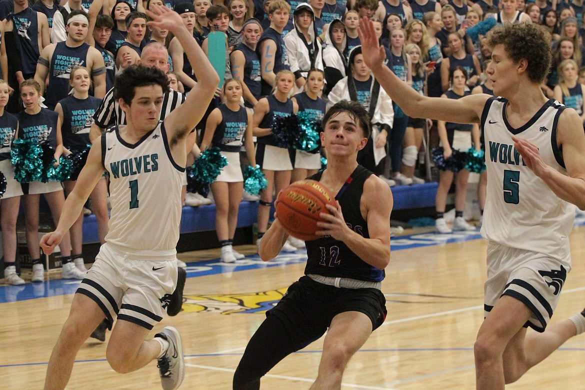 MARK NELKE/Press
Cooper Larson (12) of Coeur d'Alene drives to the basket in the second half between the defense of Reese Strawn (1) and Deacon Kiesbuy (5) of Lake City on Friday night at Coeur d'Alene High.
