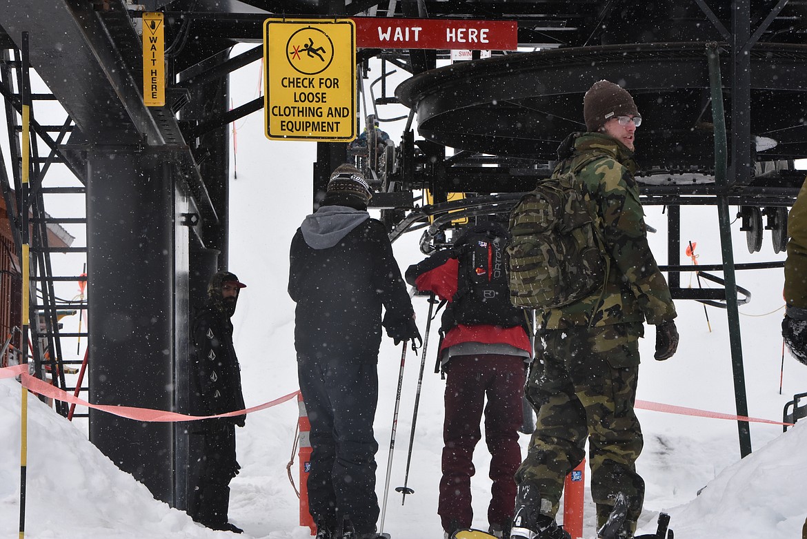 Skiers wait in the short, occasional line to hop aboard the chairlift at Turner Mountain Ski Area as snow falls on Jan. 14. (Derrick Perkins/The Western News)