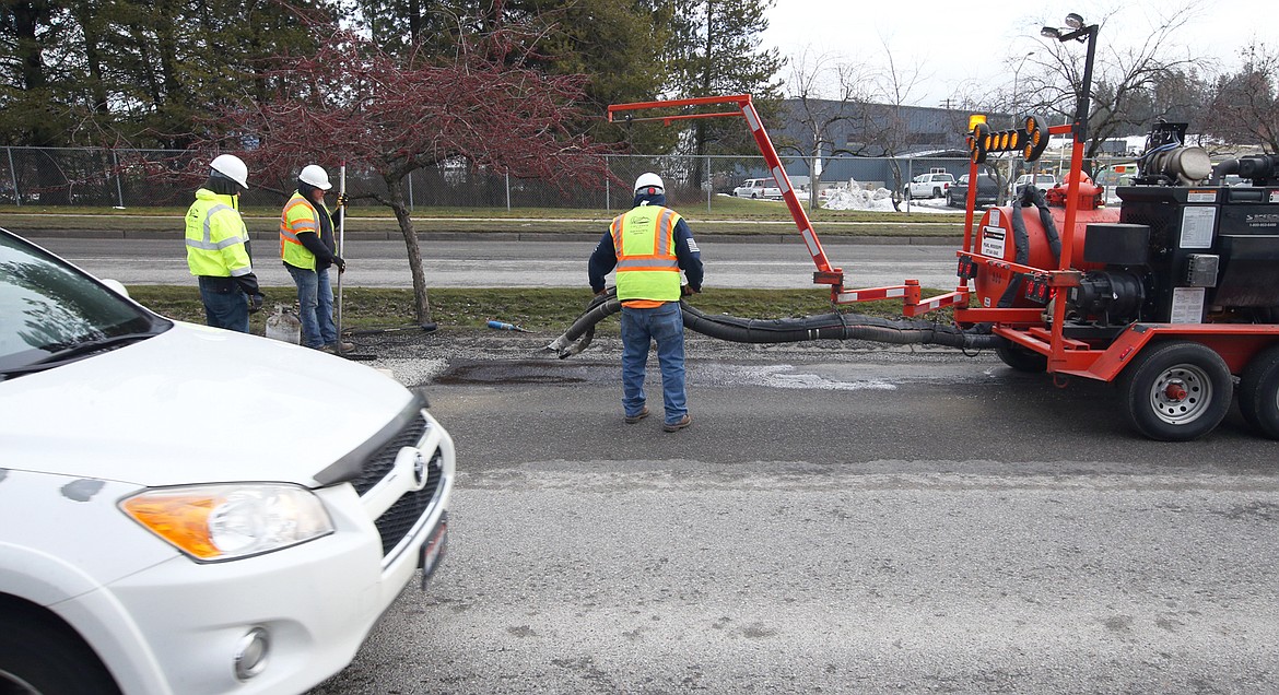 Traffic passes by city crews filing potholes on Ramsey Road on Friday.