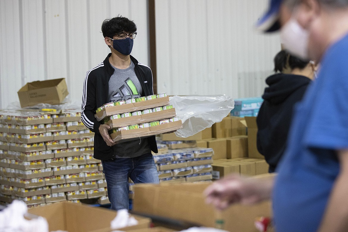 Volunteer Salok Samant carries boxes of canned food for the backpack program at Feeding America food bank in Elizabethtown, Ky., Monday, Jan. 17, 2022. Food banks across the country are experiencing a critical shortage of volunteers as the omicron variant frightens people away from group activities. (AP Photo/Michael Clubb)