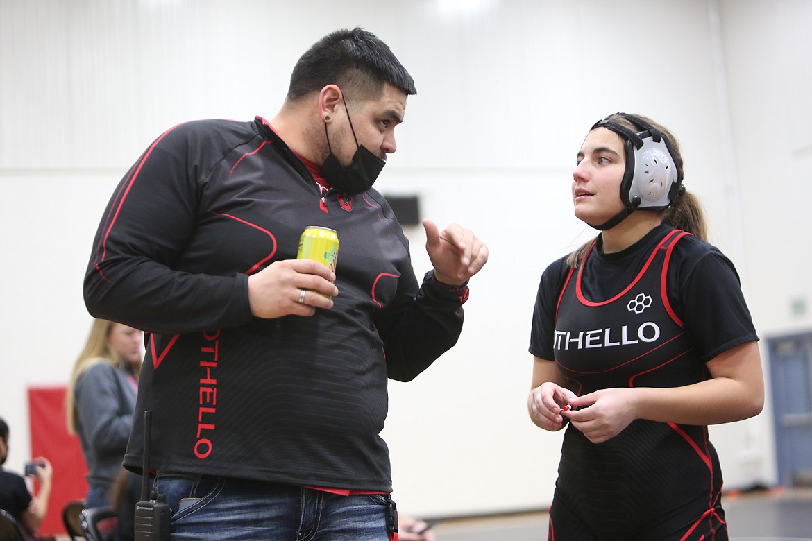 Othello High School assistant girls wrestling coach Mark De La Rosa (left) goes over a move with Lucy Giles (right) after she won a match during the Othello Lady Huskies Invitational on Friday.