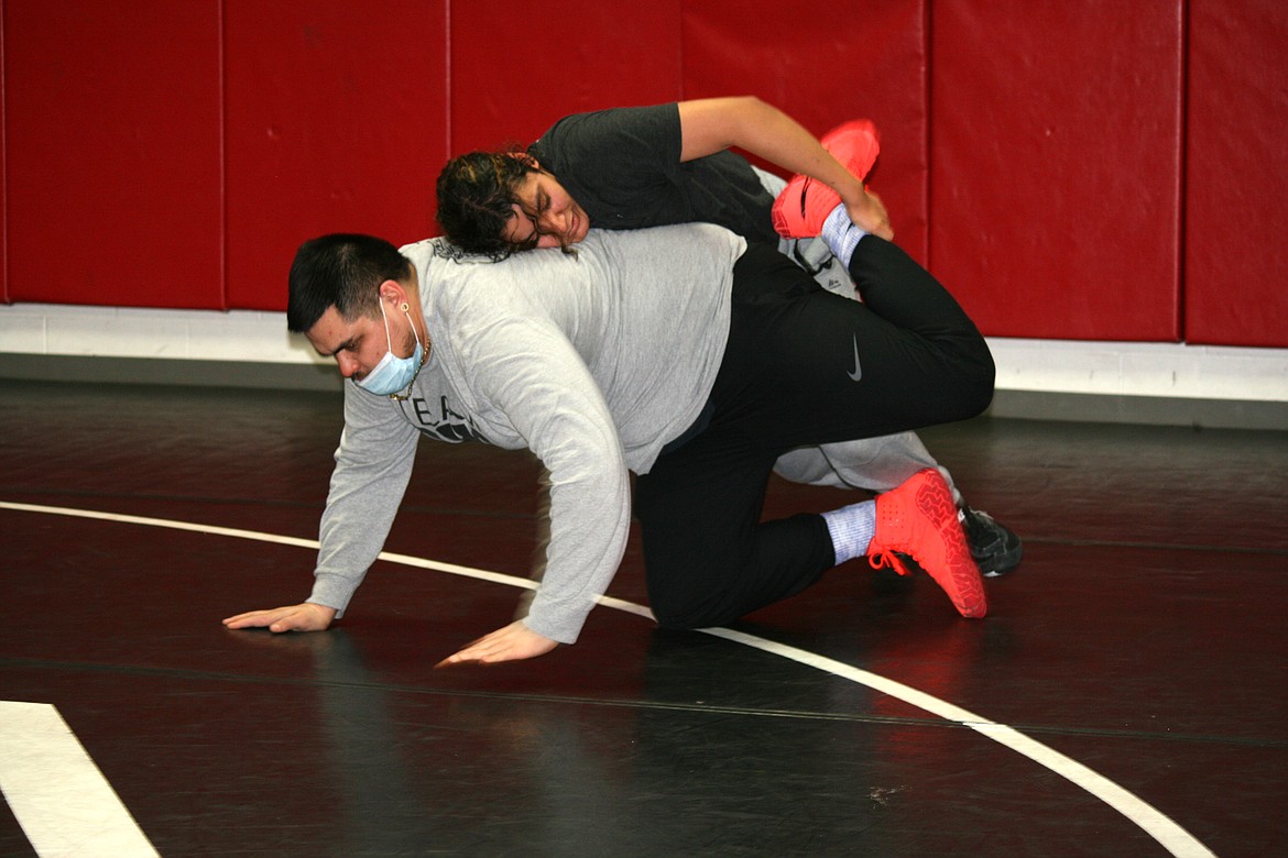 Othello High School assistant wrestling coach Mark De La Rosa (bottom) helps wrestler Aishah Mendoza with a technique during practice Jan. 13.