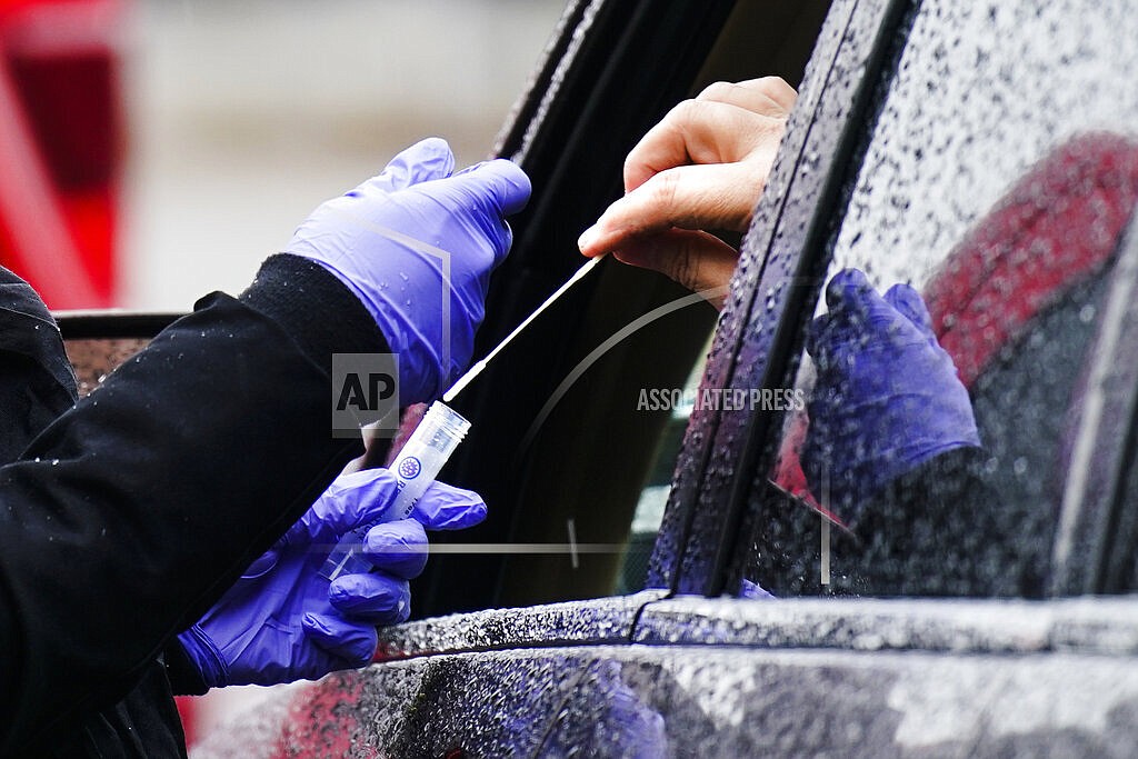 A driver places a swab into a vial at a free drive-thru COVID-19 testing site in the parking lot of the Mercy Fitzgerald Hospital in Darby, Pa., Thursday, Jan. 20, 2022. A requirement to get vaccinated against COVID-19 kicks in Thursday, Jan. 27, for millions of health care workers in about half the states. (AP Photo/Matt Rourke, File)