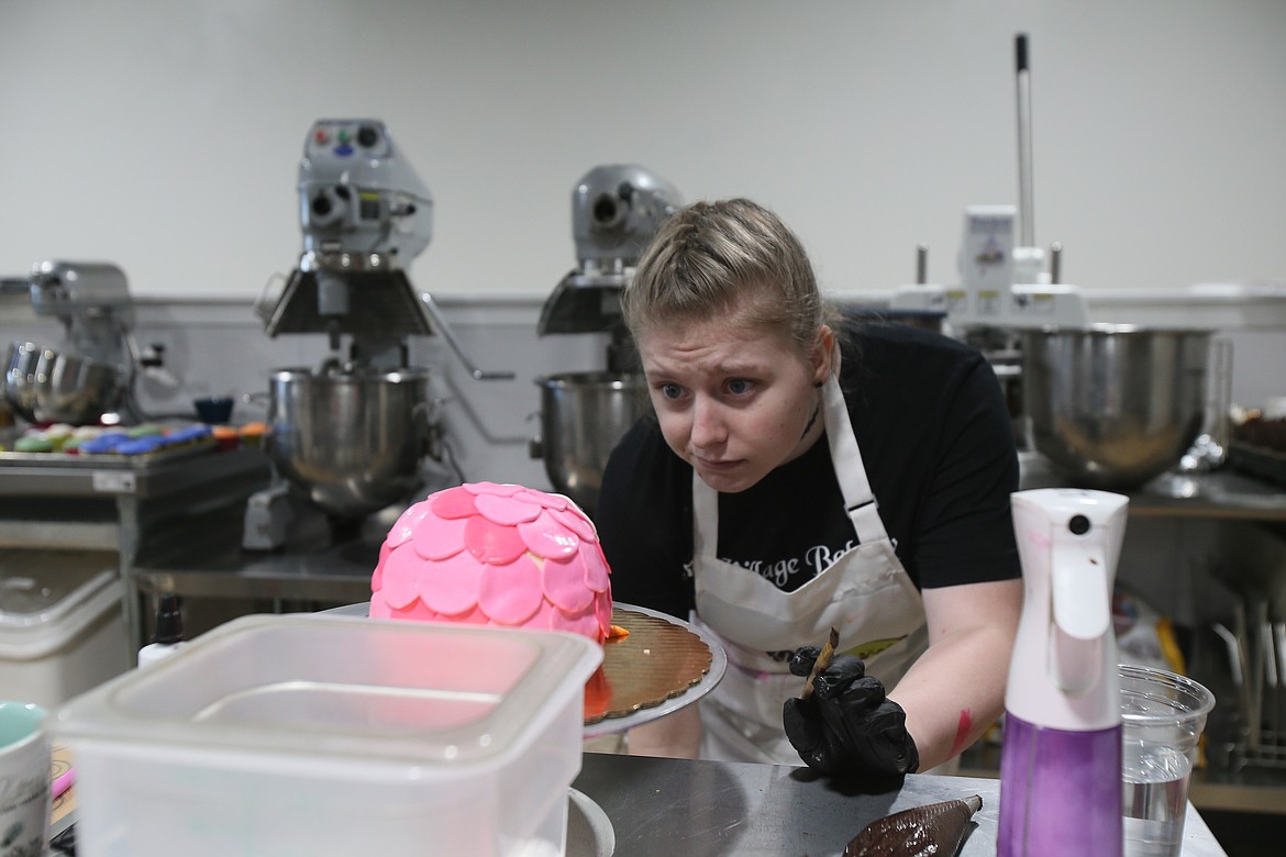 Lizzie Adams examines her work on a hot pink owl cake Thursday morning in the Village Bakery in Hayden.