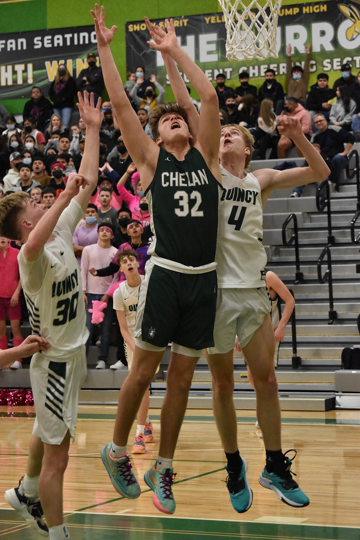 Quincy High School senior Aidan Heikes (30) and sophomore Aidan Bews (4) jump to rebound the ball at the same time that Chelan High School senior Reed Stamps (32) does on Tuesday.