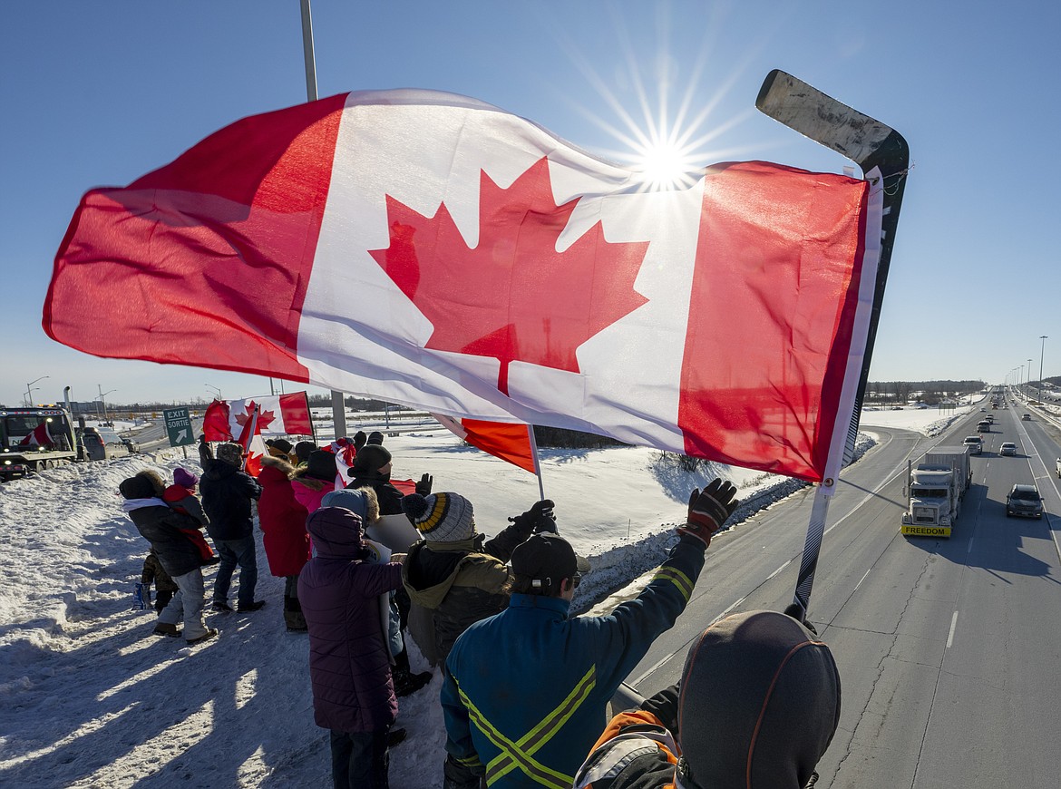 Supporters wave flags on an overpass in Kanata, Ontario, Canada,, as a trucker convoy making it's way to Parliament Hill in Ottawa to participate in a cross-country truck convoy protesting measures taken by authorities to curb the spread of COVID-19 and vaccine mandates passes by on Saturday, Jan. 29, 2022. (Frank Gunn/The Canadian Press via AP)