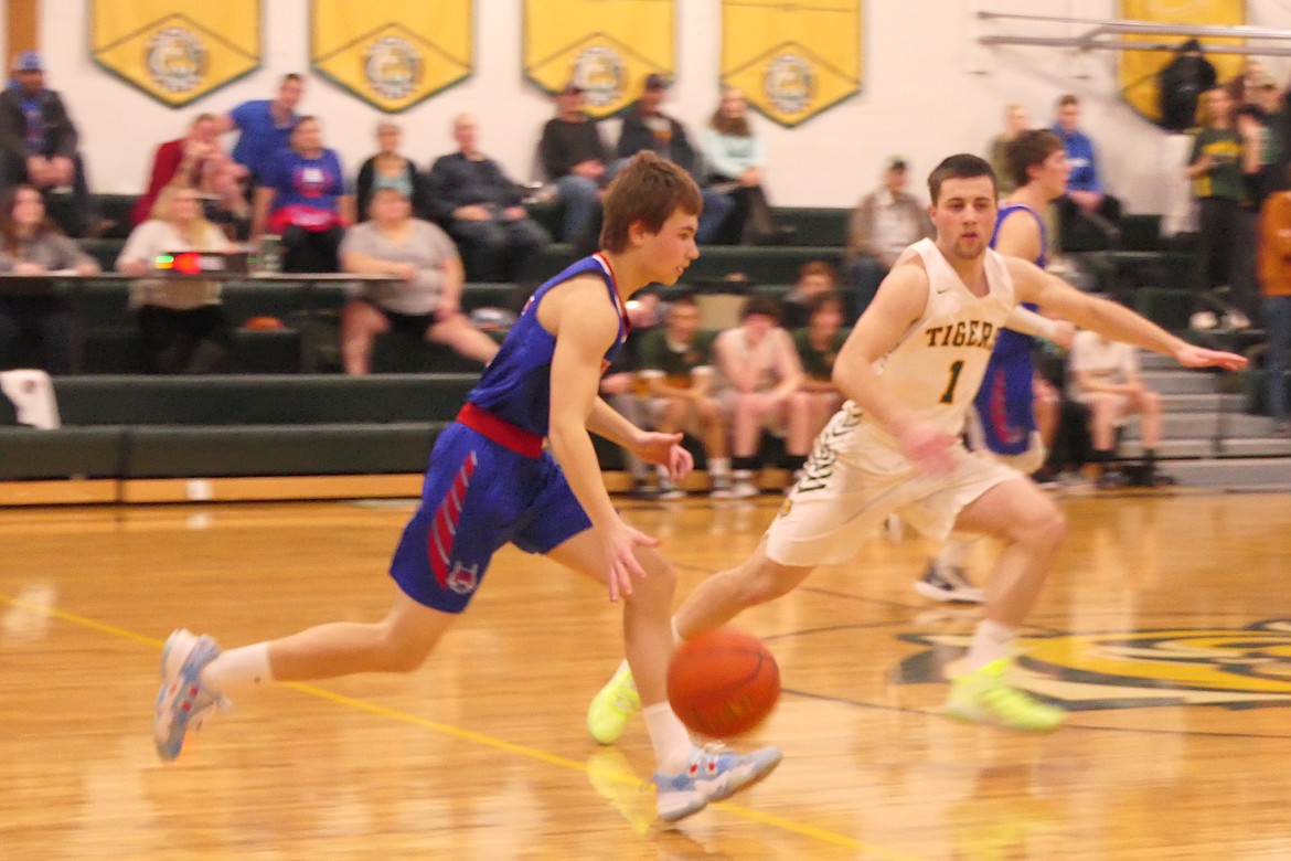 Isaac Miller, with ball, dribbles past St. Regis guard Caleb Ball during their game Wednesday in St. Regis. (Chuck Bandel MI-VP)