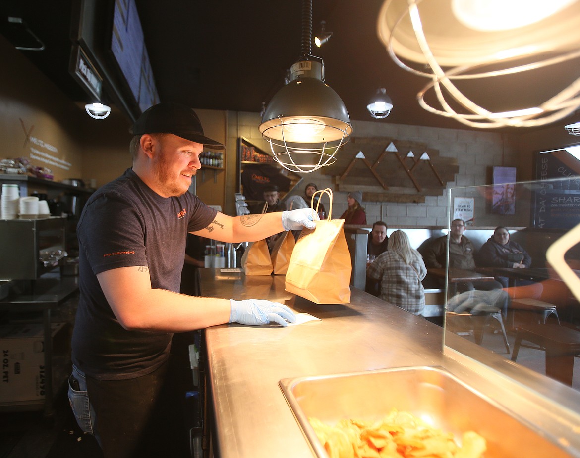 Meltz Extreme Grilled Cheese employee Kevin Howard sets a to-go order on the counter Tuesday. Meltz dedicated 40% of its Tuesday profits to help 22-year-old nursing student Tricia McCullough and her family pay for medical bills following a Dec. 26 wreck that paralyzed her.