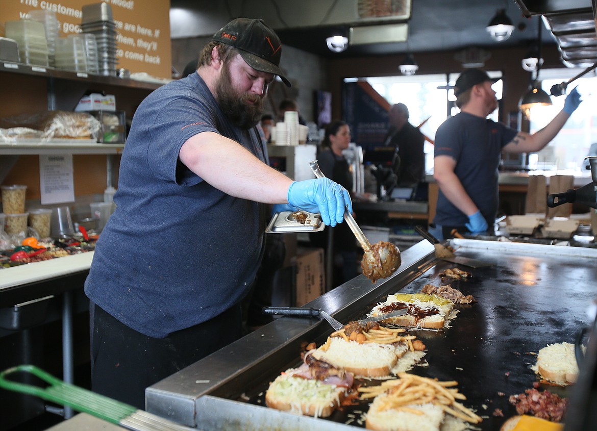 Kevin Dupont pours shiitake mushroom gravy on a sandwich in the Meltz Extreme Grilled Cheese kitchen Tuesday. Meltz is donating 40% of Tuesday's profits to help Tricia McCullough and her family pay for medical bills after she was in a car wreck that paralyzed her Dec. 26.