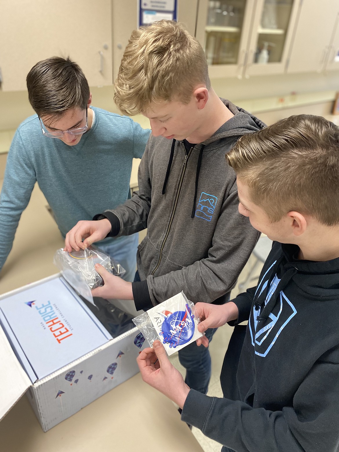 From left, Lake City High School sophomores Marcus Davis, George Lanigan and Parker Morville open a kit from NASA. The boys along with sophomore Nathan Edmonds, joined the list of 57 winning teams from schools around the country in the NASA TechRise Student Challenge, receiving a chance to make their experiment proposal a reality. Photo courtesy of Jamie Esler