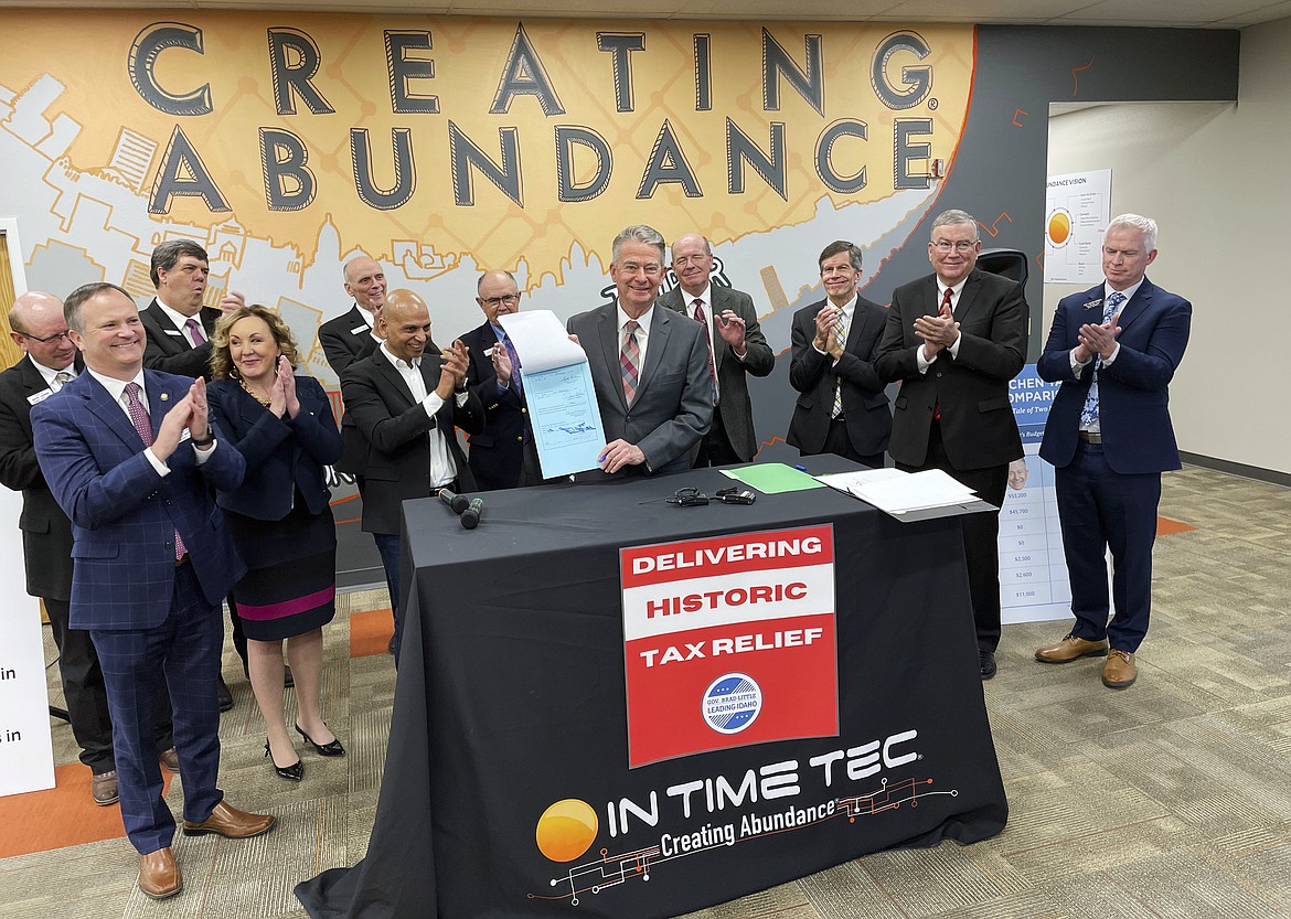 Idaho Gov. Brad Little, center, poses for photos with In Time Tec CEO Jeet Kumar, middle left, and Republican leaders from the House and Senate, and after he signed into law a $600 million tax cut, the biggest tax cut in the state's history, at software company In Time Tec in Meridian, Idaho, Friday, Feb. 4, 2022.