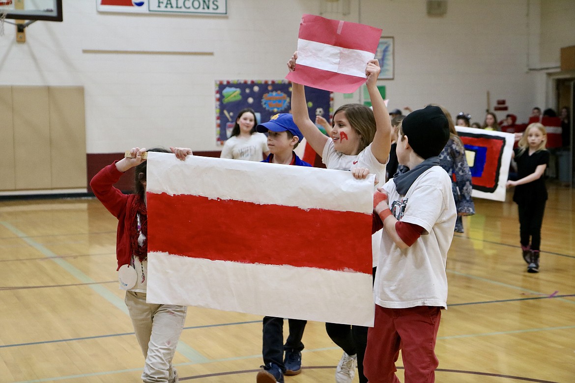 In center, Lizzie King, a third grader at Fernan STEM Academy in Coeur d'Alene, holds up a poster to represent Austria in the school's parade to welcome the opening of the Winter Olympics in Beijing on Friday. HANNAH NEFF/Press