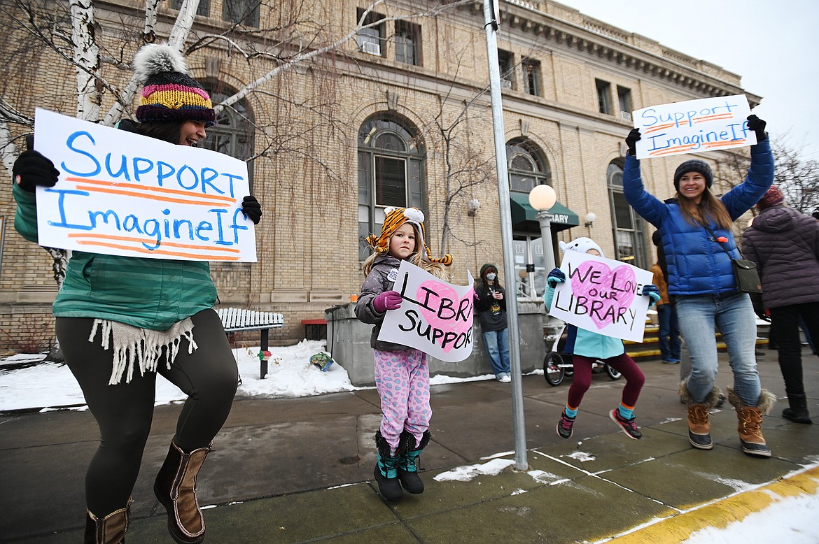 From left, Elena Martinez, Maggie Flass, Annie Flass and Katie Flass wave signs of support outside ImagineIF Library in Kalispell on Saturday, Feb. 5. (Casey Kreider/Daily Inter Lake)