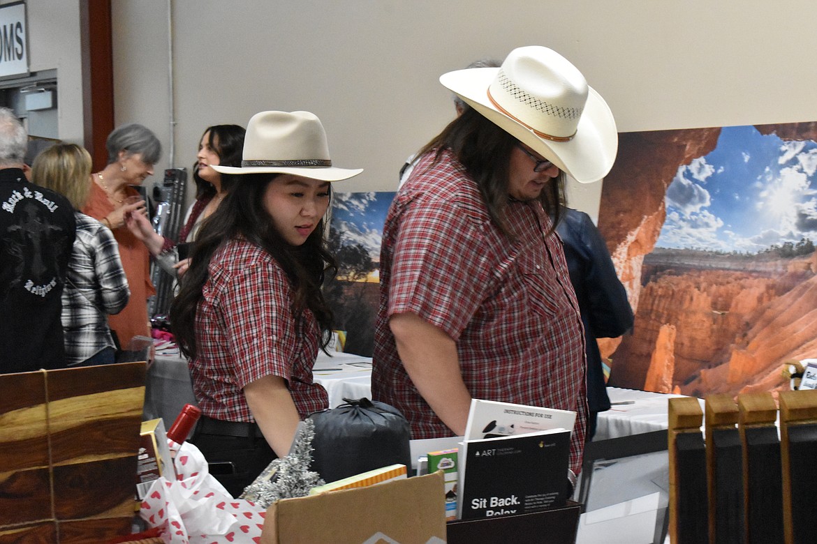 Rungnapa Chuanarom and Brad Ballinger look at items in the silent auction at the Country Sweethearts Benefit Auction on Saturday.