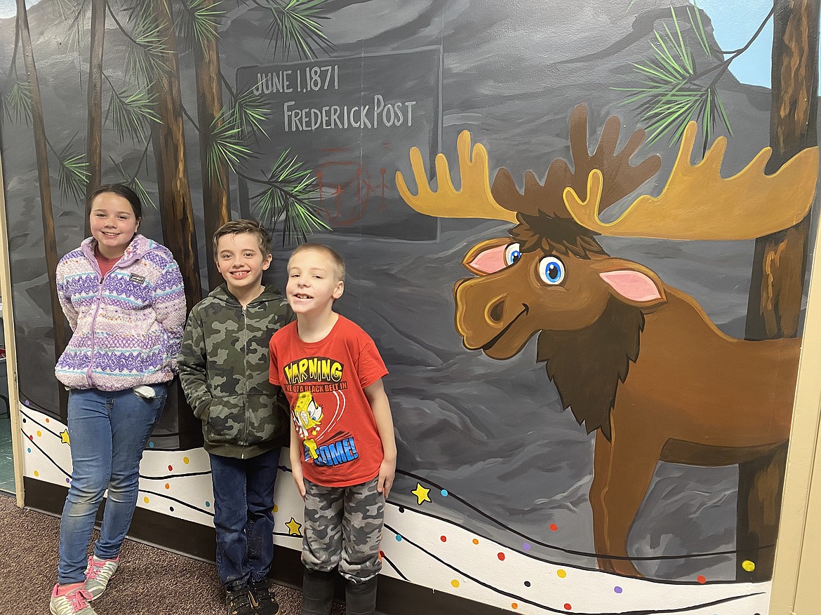 From left: Mullan Trail Elementary School students Cambria Miller, 11, Jared Jessop, 8, and Charlie Way, 7, stand in front of the history mural adorning the entryway of Mullan Trail Elementary School.