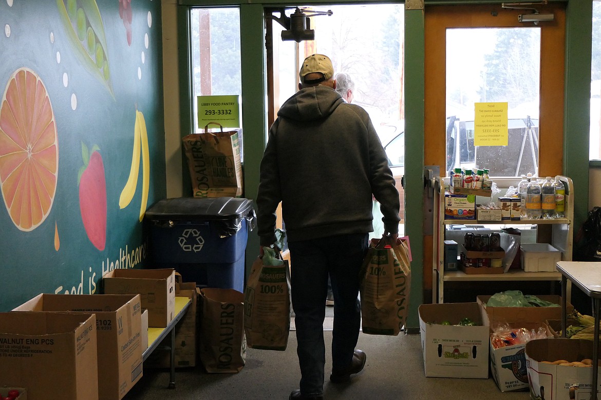 Michael Estergard, a volunteer at the Libby Food Pantry, hefts bags of goods out the rear entrance of Asa Wood Elementary School on Feb. 8. (Derrick Perkins/The Western News)