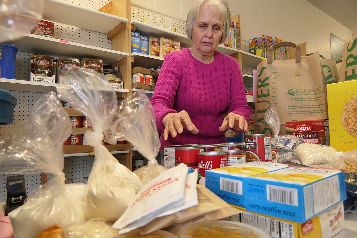 Sharon Williamson, a volunteer with the Libby Food Pantry, prepares items for outgoing bags of foodstuffs on Feb. 8. (Derrick Perkins/The Western News)
