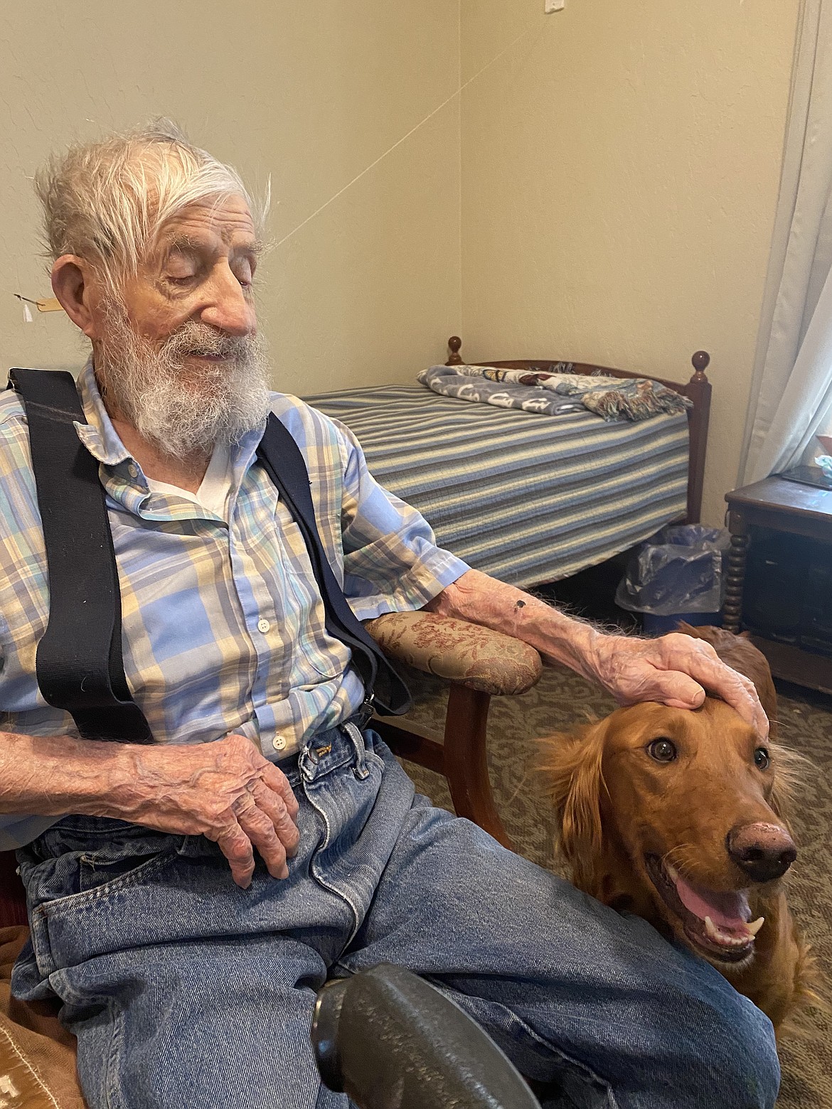 Centenarian Max Lane, an obvious dog lover, pets Molly, the house golden retriever at Wellspring Meadows Assisted Living Facility in Hayden, Tuesday. Reflecting on his 100 years of life, Lane matter-of-factly shared his best advice.