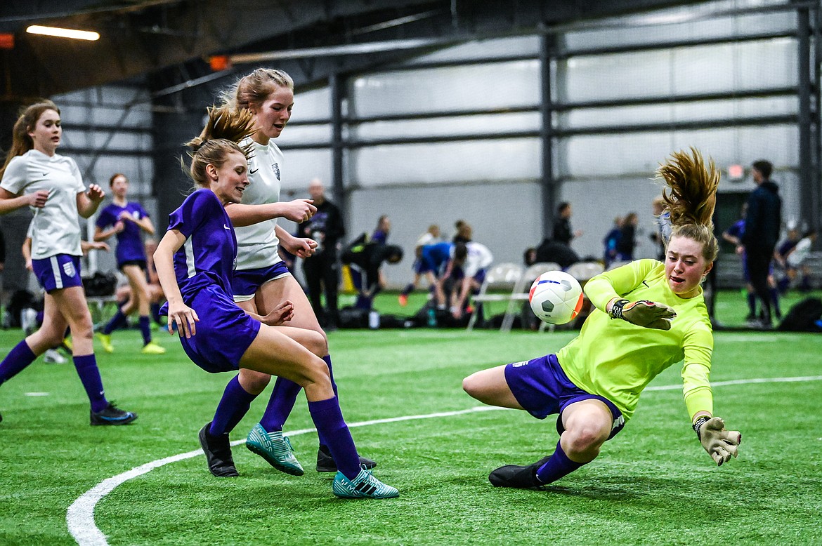 NSC 05/06G White goalkeeper Norah Schmidt (1) stops a shot on goal by NSC 05/06G Purple's Mia Stephan (3) at the Montana Indoor Soccer Championship tournament at the Flathead County Fairgrounds Trade Center building on Friday, Feb. 11. (Casey Kreider/Daily Inter Lake)