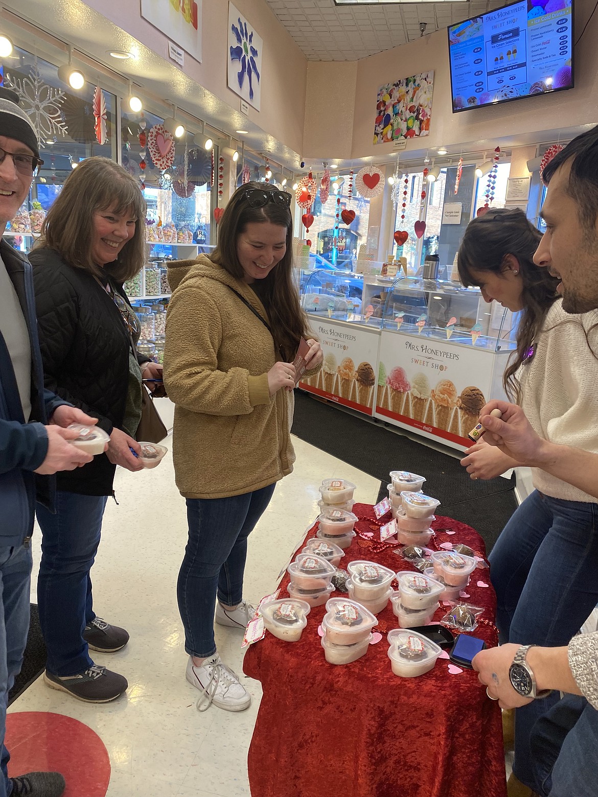 From left: Paul, Tammy and Rachel Heggenberger visit Mrs. Honeypeeps Sweet Shop, while owners of the shop Hediye and Devin Sommer describe the sweet treat offered for the annual Chocolate Affair held Friday night.