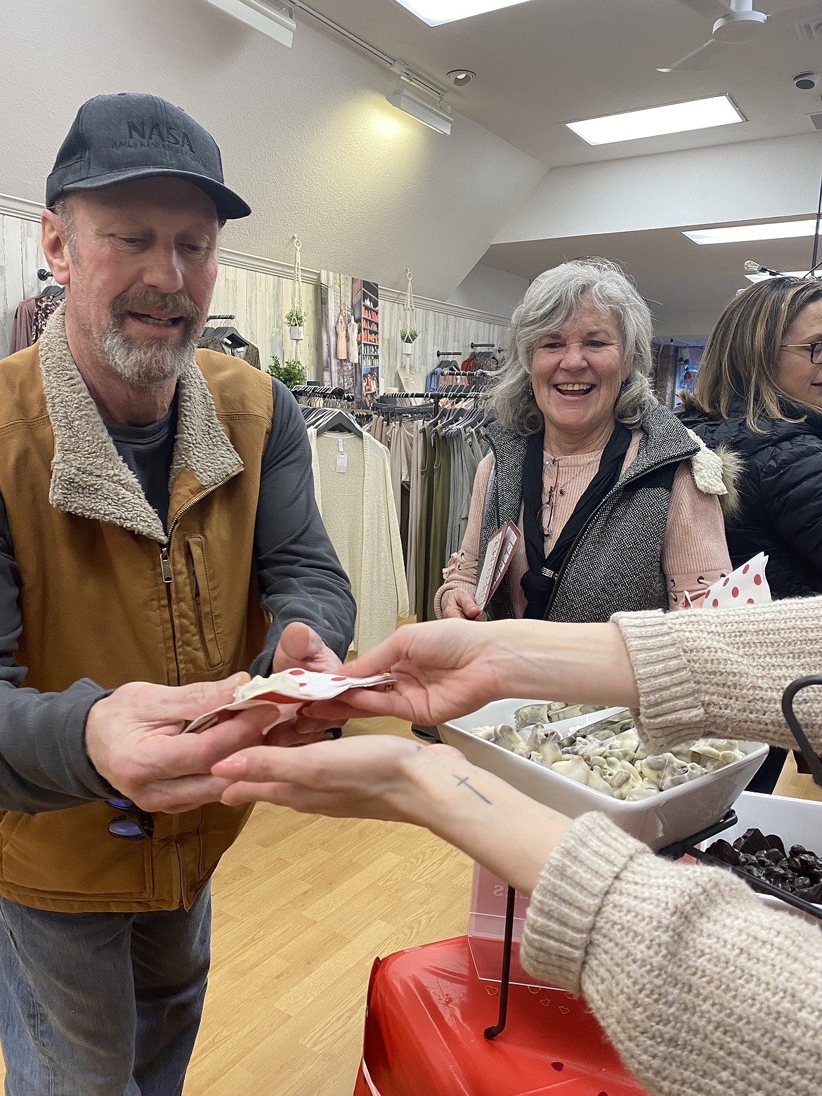 Coeur d'Alene residents Shannon and David Christensen reaching out to grab a sweet treat offered by the Garment District, on Sherman Avenue during Friday night's Chocolate Affair. For the Christensens, local events like this are the reason they love being part of the Coeur d'Alene community, they said.