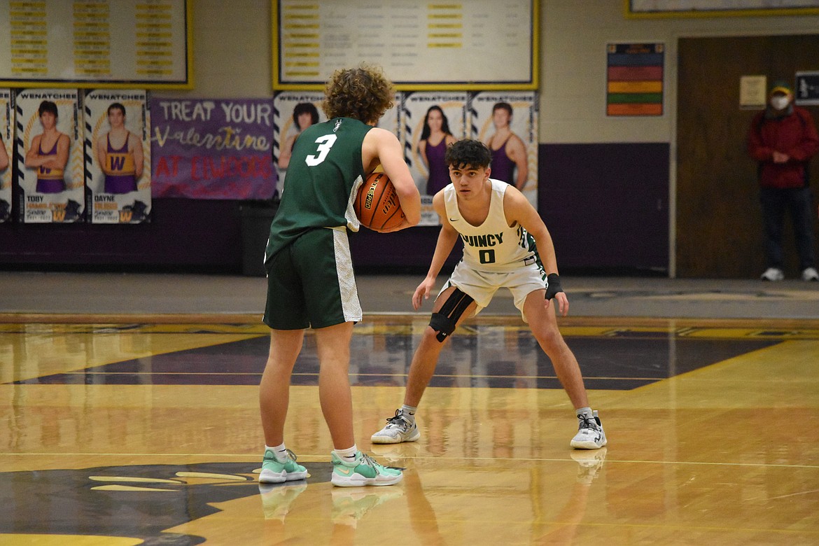 Quincy High School senior Jalen Spence (0) faces off against Chelan High School sophomore Isaac Wilson (3) during the matchup between the two teams on Feb. 11.