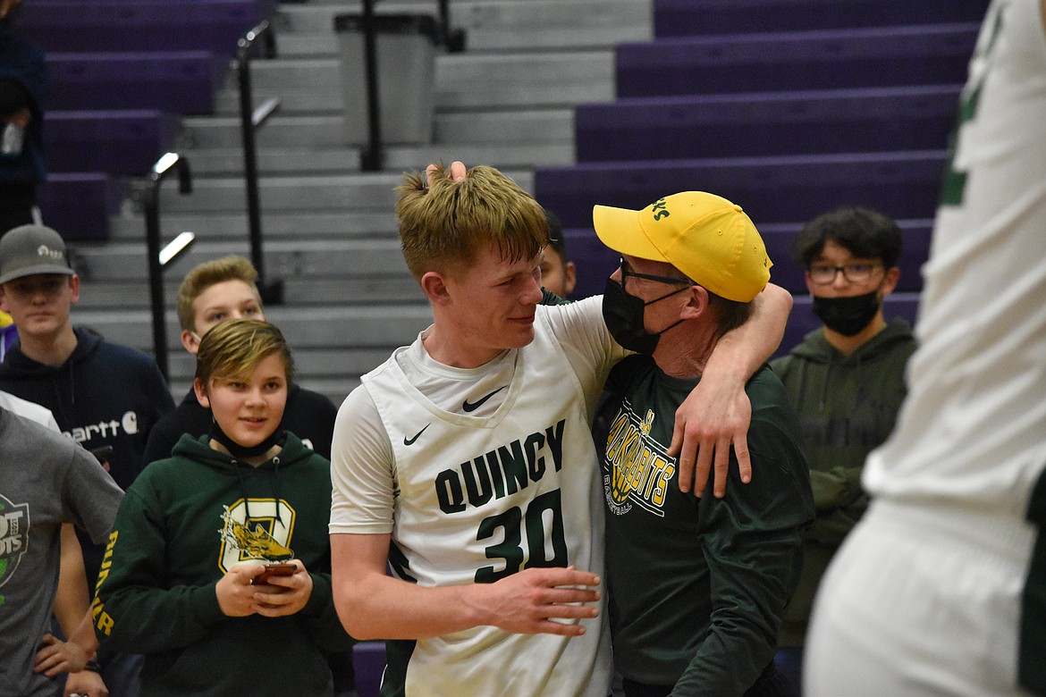 Quincy High School senior Aidan Heikes, left, is hugged by his dad, Todd Heikes, after making the winning basket to seal Quincy’s district championship on Feb. 11.