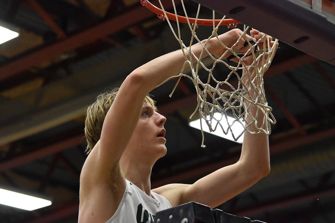 Quincy High School sophomore Aidan Bews (4) cuts the net after his team won the district championship on Feb. 11.