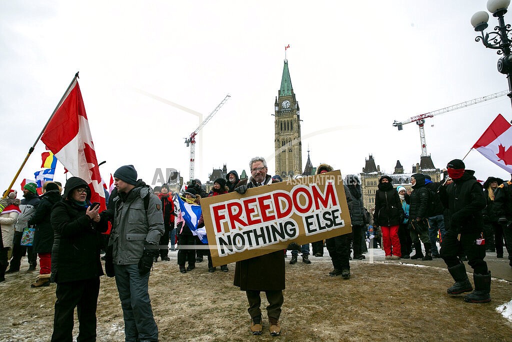 Don Stephens, 65, a retired graphic designer, holds a sign on Parliament Hill to support trucks lined up in protest of COVID-19 vaccine mandates and restrictions in Ottawa, Ontario, on Saturday, Feb. 12, 2022. Stephens said he’s come into Ottawa twice to show support for protesters there. He views them as representatives of a “silent majority that had been longing to have their voice heard.” (AP Photo/Ted Shaffrey)