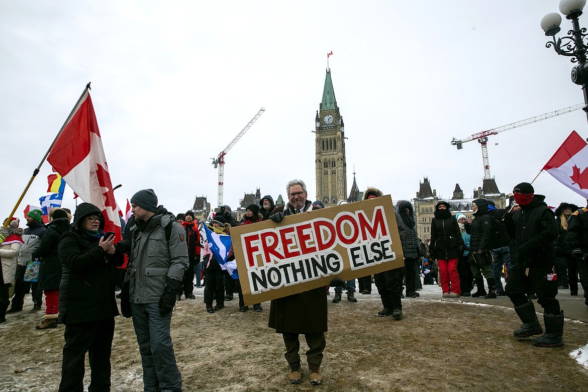 Don Stephens, 65, a retired graphic designer, holds a sign on Parliament Hill to support trucks lined up in protest of COVID-19 vaccine mandates and restrictions in Ottawa, Ontario, on Saturday, Feb. 12, 2022. Stephens said he’s come into Ottawa twice to show support for protesters there. He views them as representatives of a “silent majority that had been longing to have their voice heard.” (AP Photo/Ted Shaffrey)