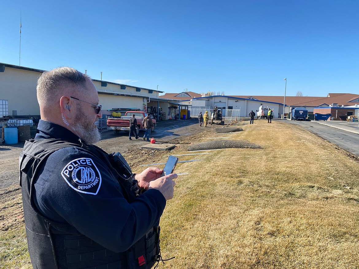 Warden Police Chief Rick Martin communicates with other officials as fire crews and utility workers address a natural gas leak at Warden High School on Monday. The augur in the background is suspected of having caused the leak.